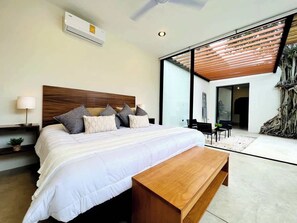 Quarto moderno com uma cama grande, um banco de madeira, uma mesinha de cabeceira e um ventilador de teto.