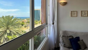 A room with a large window, a sofa, and a wall-mounted light fixture.