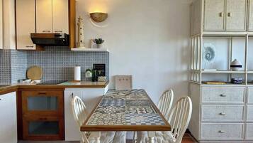 Una cocina compacta con salpicadero de azulejos, encimera de madera y una mesa con sillas.
