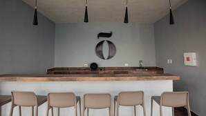A modern kitchen with a central island, bar stools, pendant lighting, and a wall-mounted number '50' sign. - Loft al norte de Mérida con increíble vista (Merida)