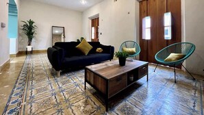 A living room with a sofa, coffee table, and two chairs. - Casa Álamo in Downtown Mérida: 1br+Private Pool (Merida)
