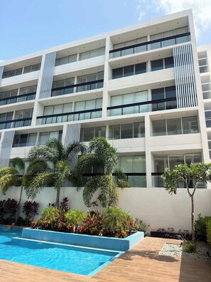 Ein mehrstöckiges Hotel mit Pool und gepflegtem Garten.