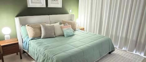 A bedroom with a bed, a nightstand, a ceiling fan, and a window with curtains.