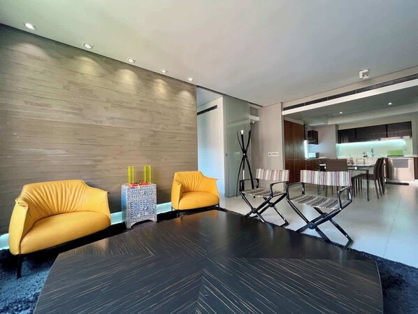 Un espace de vie moderne avec un plancher en bois foncé, deux canapés jaunes, une petite table d’appoint et une table basse noire.