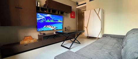 A modern living room with a grey sofa, a flat-screen TV, a bench, and built-in wooden cabinets.