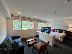 Een hotelkamer met een bed, een televisie, een bank, een salontafel en een stoel.