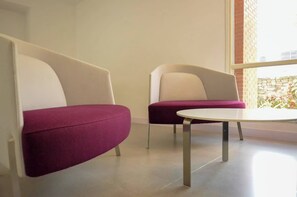 Ein modernes Interieur mit zwei Sitzbereichen mit Polstern und einem runden Tisch.