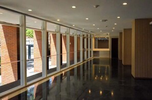 A corridor with glass walls, a polished floor, and recessed lighting. - Altamira Romántico: Nido para Parejas (Caracas)