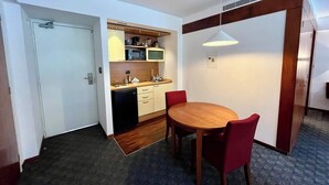 A compact room with a dining table and chairs, a kitchenette with a microwave, and a door leading to another room. - Tu escape en caracas, apartamento moderno (Caracas)