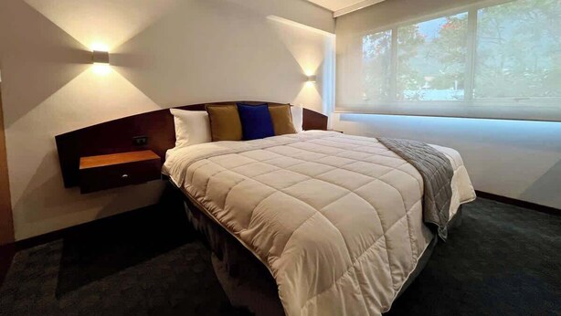 A modern bedroom with a bed, bedside tables, and a window. - Tu escape en caracas, apartamento moderno (Caracas)