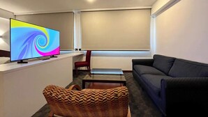 A modern living room with a flat-screen TV, a sofa, a red chair, and a glass coffee table. - Tu escape en caracas, apartamento moderno (Caracas)