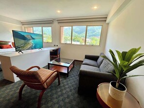 A hotel room with a bed, a desk, a sofa, and a large window with a view. - Tu Rincón en Altamira: ¡Céntrico y Nuevo! (Caracas)