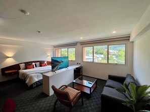 A modern hotel room with a bed, a TV, a desk, and a sofa. - Tu Rincón en Altamira: ¡Céntrico y Nuevo! (Caracas)