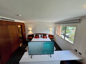 Een hotelkamer met een bed, een bureau met een flatscreen televisie, een kledingkast en een raam met uitzicht.