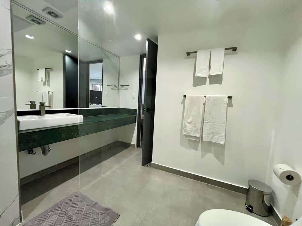 A modern bathroom with a glass shower enclosure, a white sink, and a toilet.