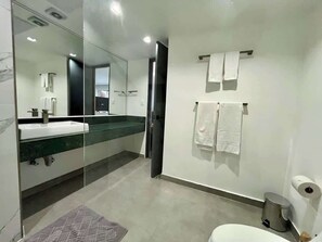 Ein modernes Badezimmer mit Duschkabine aus Glas, einem weißen Waschbecken und einer Toilette.