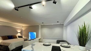 A modern hotel room with a bed, a desk with a computer, a television, and a plant. - Disfruta de esta acogedora habitación en Caracas (Caracas)
