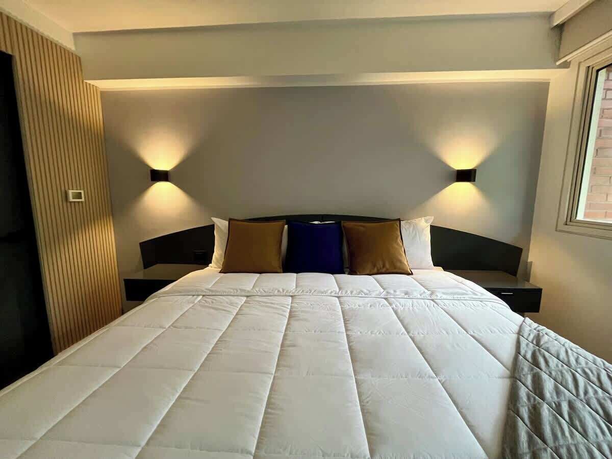 Ett hotellrum med en stor säng, två sängbord och väggmonterad belysning.
