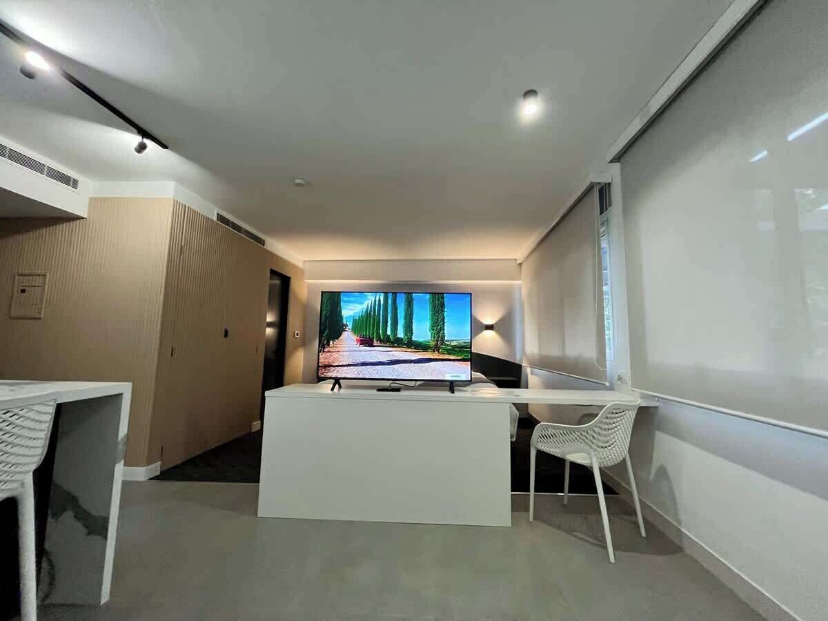 Ein modernes Hotelzimmer mit Flachbildfernseher, Schreibtisch und Stuhl.