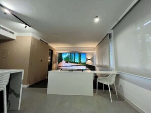Ein modernes Hotelzimmer mit Flachbildfernseher, Schreibtisch und Stuhl.