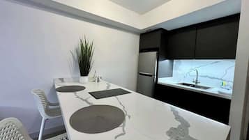 A modern kitchen with a marble countertop, a built-in oven, and a refrigerator.
