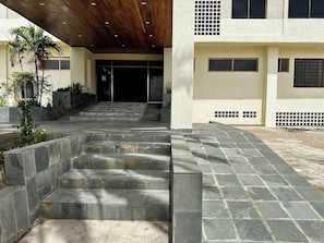 A set of stone steps leading to a building entrance with a wooden ceiling.