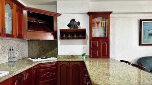 Une cuisine dotée de plans de travail en granit, de meubles en bois, d’une cuisinière encastrée et d’une décoration murale en forme de poisson.