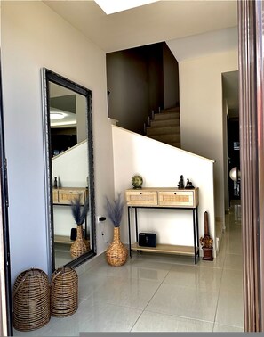 Ein modernes Interieur mit einem großen Spiegel, einem Konsolentisch mit Dekoration und einer Treppe.