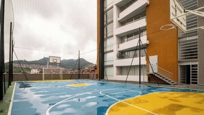 An indoor basketball court with a net, surrounded by a building with multiple floors and a view of a distant town.
