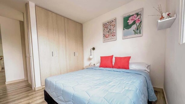 A bedroom with a bed, a wardrobe, and two wall-mounted pictures.