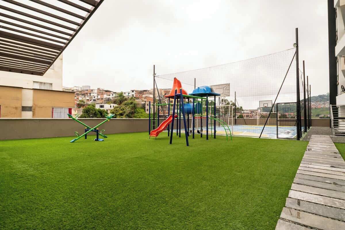 An outdoor play area with artificial grass, a slide, and a climbing structure.