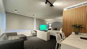 Una camera d'albergo moderna con un letto grande, una scrivania, una televisione e un'area salotto con un divano e delle poltrone.