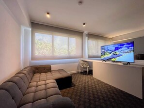 Una sala de estar moderna con un sofá seccional, un televisor de pantalla plana y un pequeño escritorio.