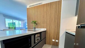 Una cucina moderna con forno integrato, lavello e parete decorata in legno.