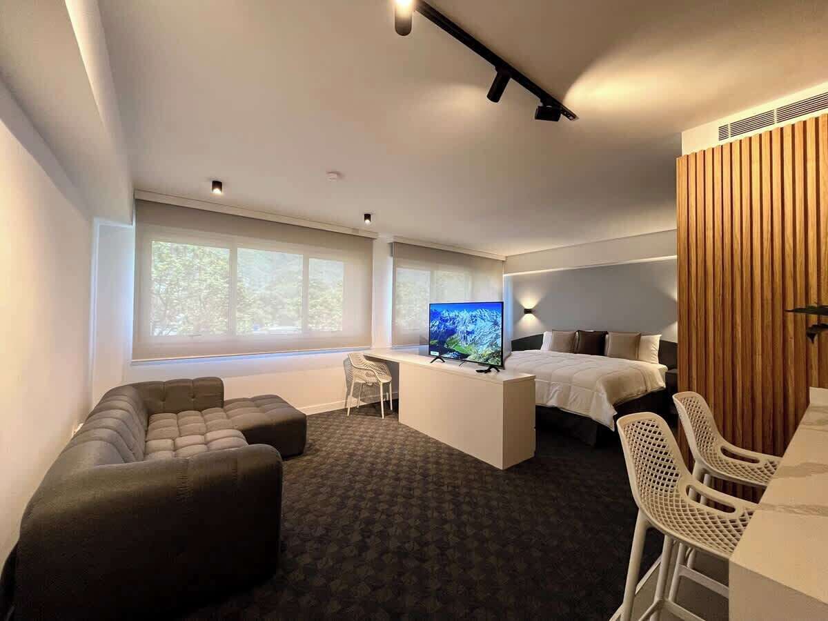 Une chambre d’hôtel moderne équipée d’un canapé, d’un petit bureau, d’un lit et d’une télévision.