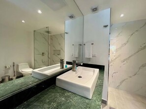 Ein modernes Badezimmer mit zwei Waschbecken, einer Duschkabine aus Glas und Marmorböden.