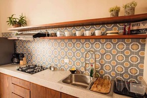 A kitchen with a gas stove, sink, and a backsplash with a geometric pattern. - Central Mérida Home w/ Patio, Steps to Market (Merida)