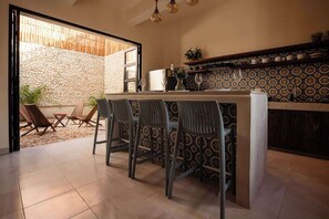 A kitchen with a stone wall, a bar area with chairs, and a tiled floor. - Central Mérida Home w/ Patio, Steps to Market (Merida)