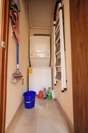 A narrow hallway with a mop leaning against the wall, a blue bucket, and cleaning supplies. - Central Mérida Home w/ Patio, Steps to Market (Merida)
