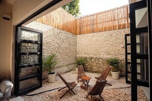 An outdoor seating area with stone walls, wooden furniture, and potted plants. - Central Mérida Home w/ Patio, Steps to Market (Merida)