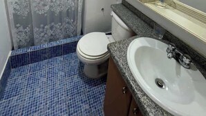 A bathroom with a toilet, sink, and shower curtain. - Tu Refugio Porlamar | A pasos de Playa Veleros (Porlamar)
