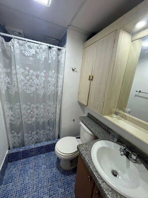 A bathroom with a toilet, sink, and shower curtain. - Tu Refugio Porlamar | A pasos de Playa Veleros (Porlamar)