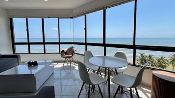 Un salon moderne avec une grande fenêtre, une table ronde entourée de chaises, un canapé et une table basse.