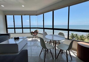 Un salon moderne avec une grande fenêtre, une table ronde entourée de chaises, un canapé et une table basse.