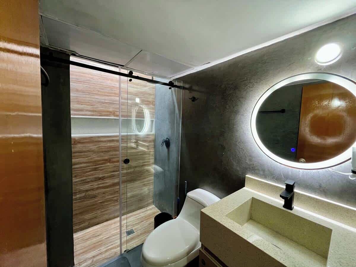 Ein Badezimmer mit Dusche, Toilette, Waschbecken und Spiegel.