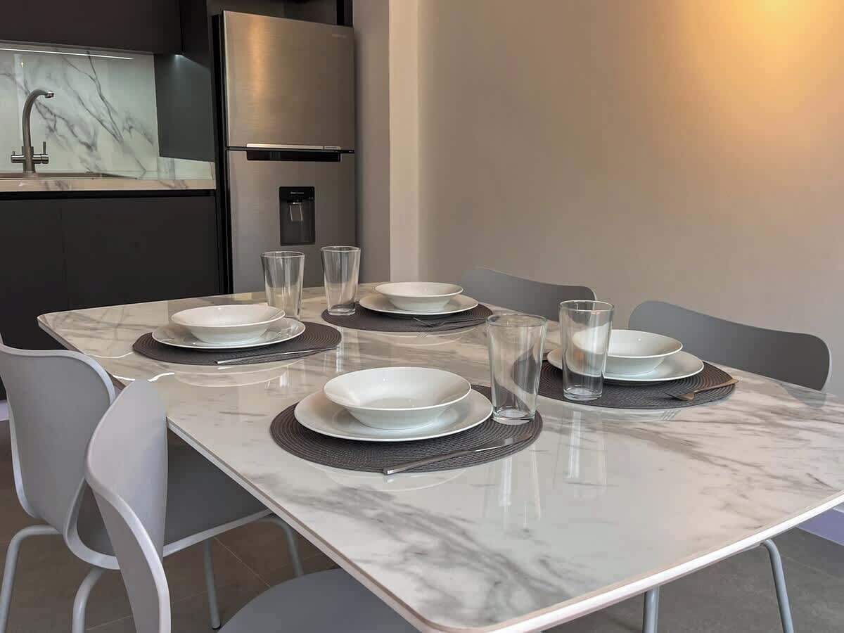 Mesa de comedor puesta con platos, vasos y dispensador de agua.