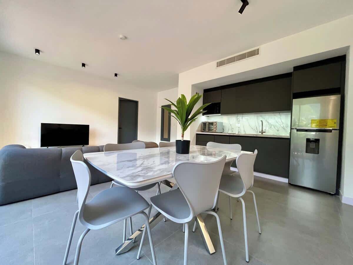 Eine moderne Küche mit Einbauofen, Kühlschrank und einem Essbereich mit einem Marmortisch und Stühlen.