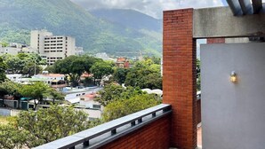 Un balcone con vista su un panorama urbano, che include edifici e una montagna.