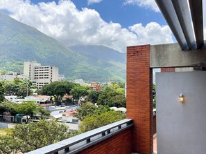 A balcony with a view of a cityscape, including buildings and a mountain. - PH Altamira: Vistas Ávila & Terraza Panorámica (Caracas)