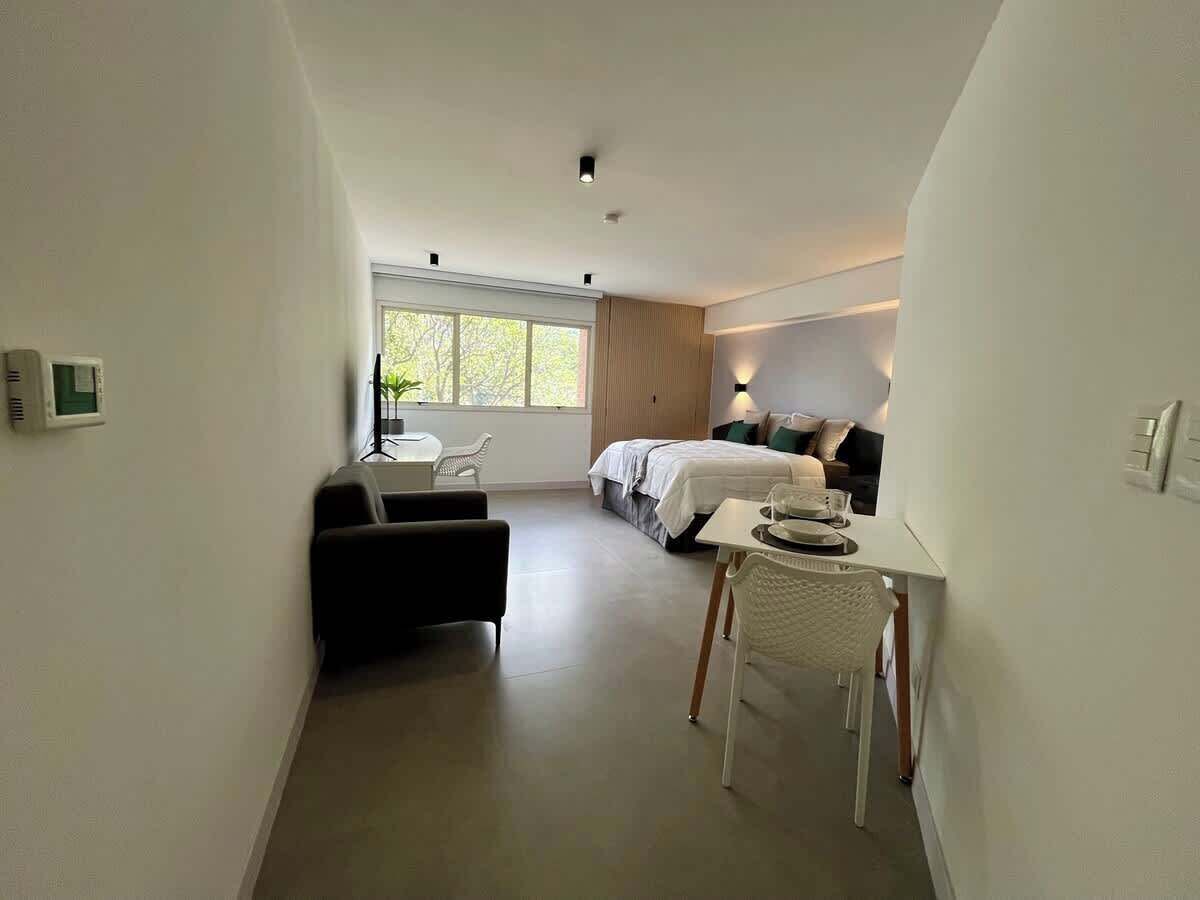 Una habitación de hotel moderna con cama, escritorio, silla y un pequeño rincón de descanso.